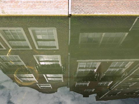 sich im Wasser spiegelnde Häuser an einer niederländischen Gracht, in der sich ein versenktes Fahrrad befindet