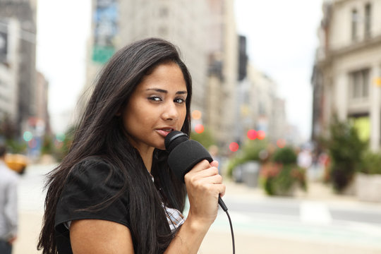 A Female Newscaster Talking Into Her Microphone.