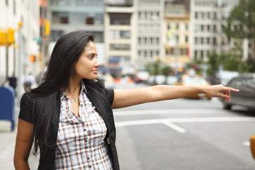 A woman hailing a taxi on a city street.