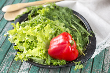 Dish with pepper and green-stuff on a wooden table