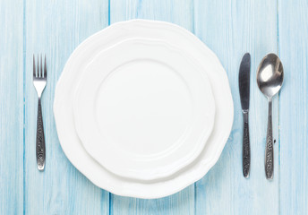 Empty plate and silverware over wooden table