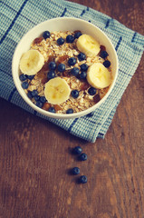 Oat flakes with fresh blueberries and banana in a white bowl on a wooden surface