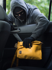 Transportation crime concept .Thief stealing bag from the car