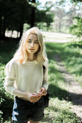 portrait of a beautiful young blonde in the forest, walking in the woods
