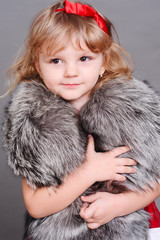 Cute little girl wearing fur clothes. Looking at camera. Childhood.