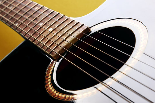 Detail of black acoustic guitar on yellow background