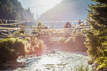 River with hanging pedestrian bridge and nepalese flags