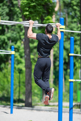  athlete doing pull-up on horizontal bar.Mans fitness outdoor.