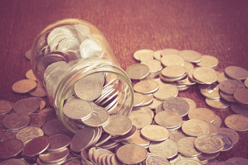Coins spilling out of a glass bottle with filter effect retro vi