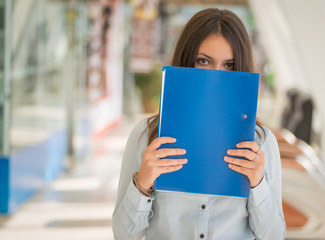 Young woman with blue folder in office.