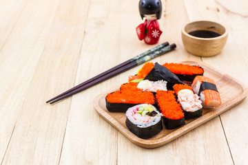 Japanese sushi traditional food on wooden plate with kokeshi.