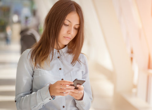Young businesswoman inside office with smartphone.