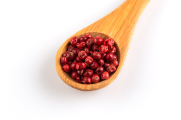 red peppercorns in wooden spoon isolated