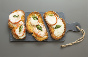 Basil tomato and cheese bruschetta over a slate rock board