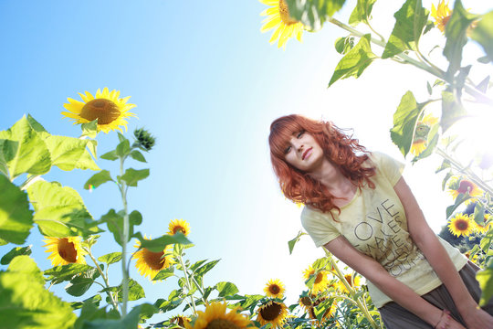 Красивая рыжая девушка в подсолнухах