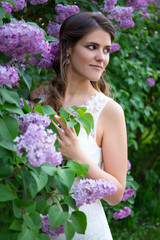 beautiful bride posing near blooming lilac tree