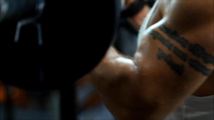 a man in a sports body is engaged in the gym lifting heavy weights with emotional stress. The men in club up the heavy equipment for bodybuilding and he have strong hands.