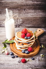 Pancakes with fresh summer berries and bottle of milk