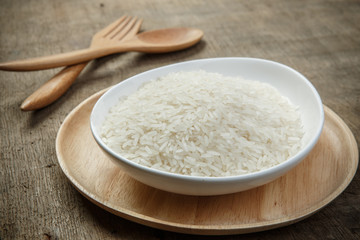 Fototapeta na wymiar White rice grains with wooden spoon on wooden table - soft focus