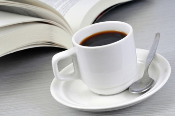 Tasse de café noir près d'un livre ouvert