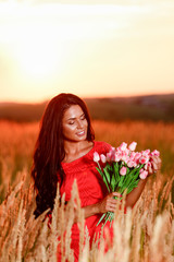 beautiful brunette woman in red dress with tulips in hands on a