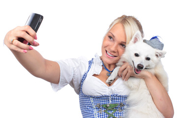 Junge Frau im Dirndl macht Selfie von sich und ihrem Spitz