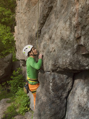 A young rock climber climbs difficult wall.
