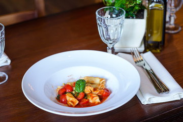Italian dish of pasta and tomato/Italian dish of pasta and tomato served on a wooden table in a restaurant