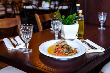 Italian dish of small fish with slices of tomato/Traditional Italian dish of fried small fish with slices of tomatoes and bread on a dark wooden table