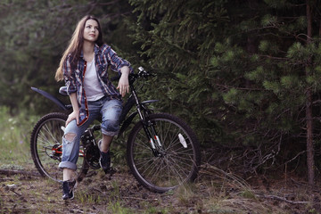Fototapeta na wymiar young girl on a sports bike in a summer forest