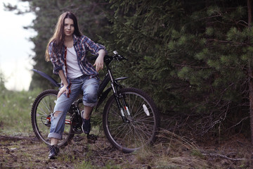 Fototapeta premium young girl on a sports bike in a summer forest
