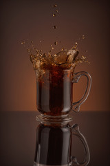 Ice cappuccino splash, refreshing mug of coffee on brown background.