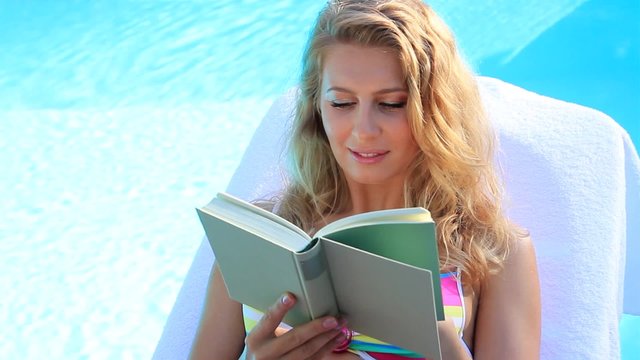 young blond woman in the summer holidays reading a book