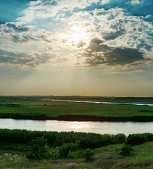 dramatic cloudy sky over river in green canes