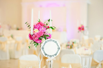 Nice flowers with candles in vase on table in restaurant in wedding day