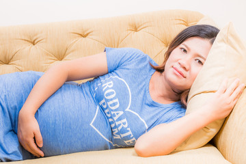 Pregnant woman relaxing at home on sofa