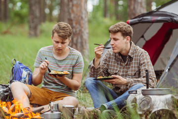 Naklejka na ściany i meble young men are heated in a fire and cook out on a summer camp