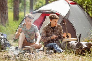 young men are heated in a fire and cook out on a summer forest