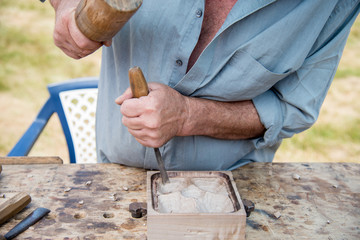 Old woodcarver working with mallet and chiesel, vintage style
