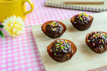 Chocolate balls with fancy topping on wooden plate and spoon