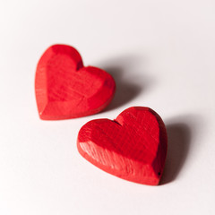 Obraz na płótnie Canvas Love and Valentines: pair of hearts. A pair of red wooden carved hearts isolated on white.