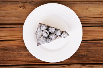 Piece of delicious chocolate pie with fresh blackberries decorat