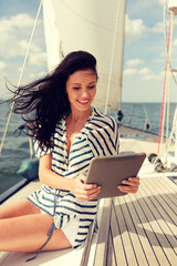 smiling woman sitting on yacht with tablet pc