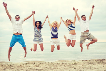 smiling friends in sunglasses walking on beach