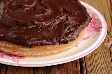 Round homemade chocolate cake covered with thick ganache in whit