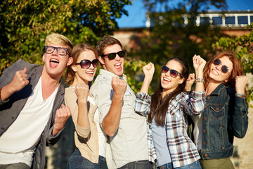 group of happy friends showing triumph gesture