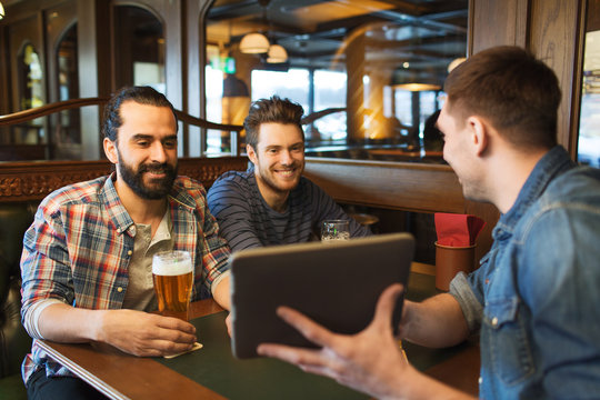 male friends with tablet pc drinking beer at bar