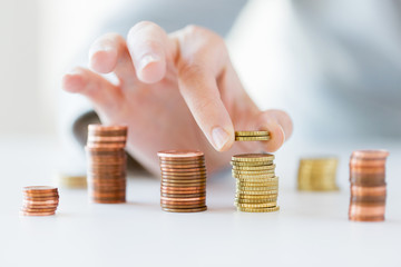 close up of female hand putting coins into columns