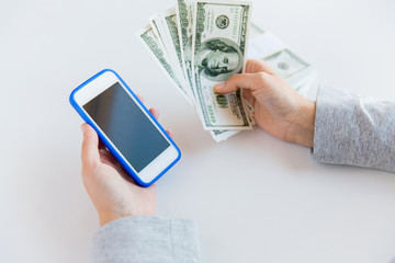 close up of woman hands with smartphone and money