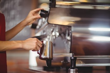 Fototapeta na wymiar Barista steaming milk at the coffee machine